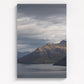 Moody storm clouds, sun-lit peak over Lakeside peaks in Queenstown New Zealand