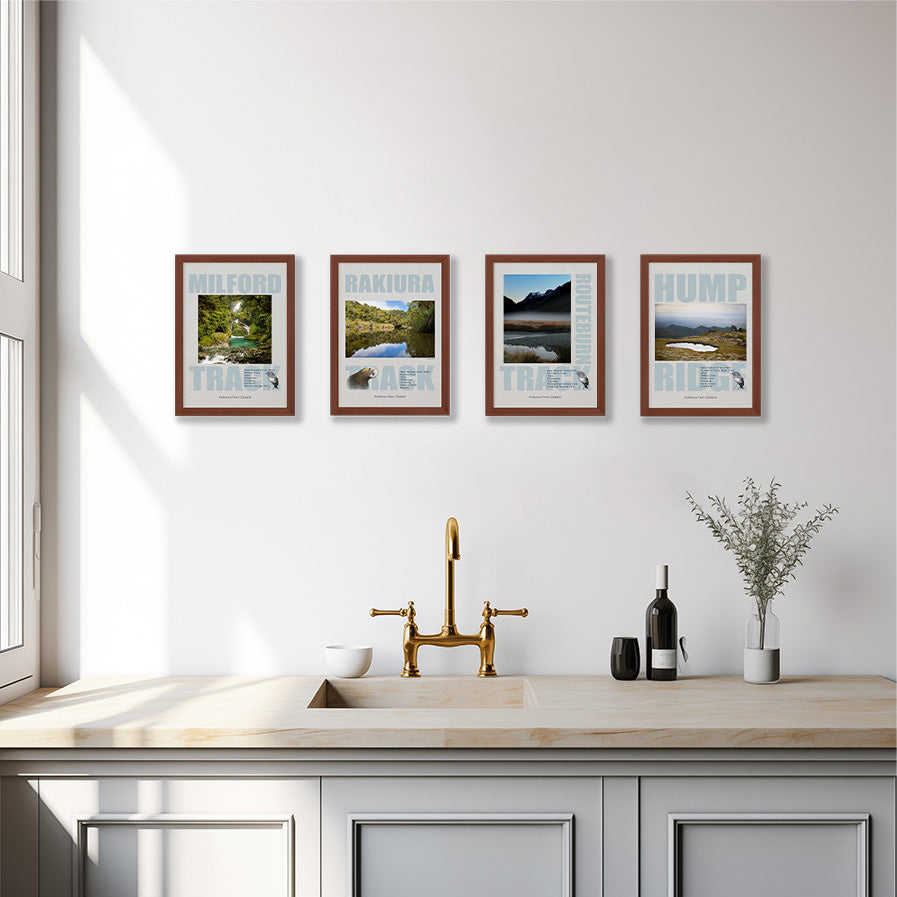 Four framed Great Walks posters on a white wall above a kitchen sink. The prints show wild national parks landscapes.