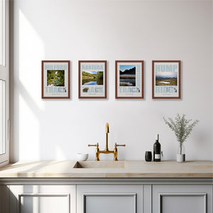 Four framed Great Walks posters on a white wall above a kitchen sink. The prints show wild national parks landscapes.