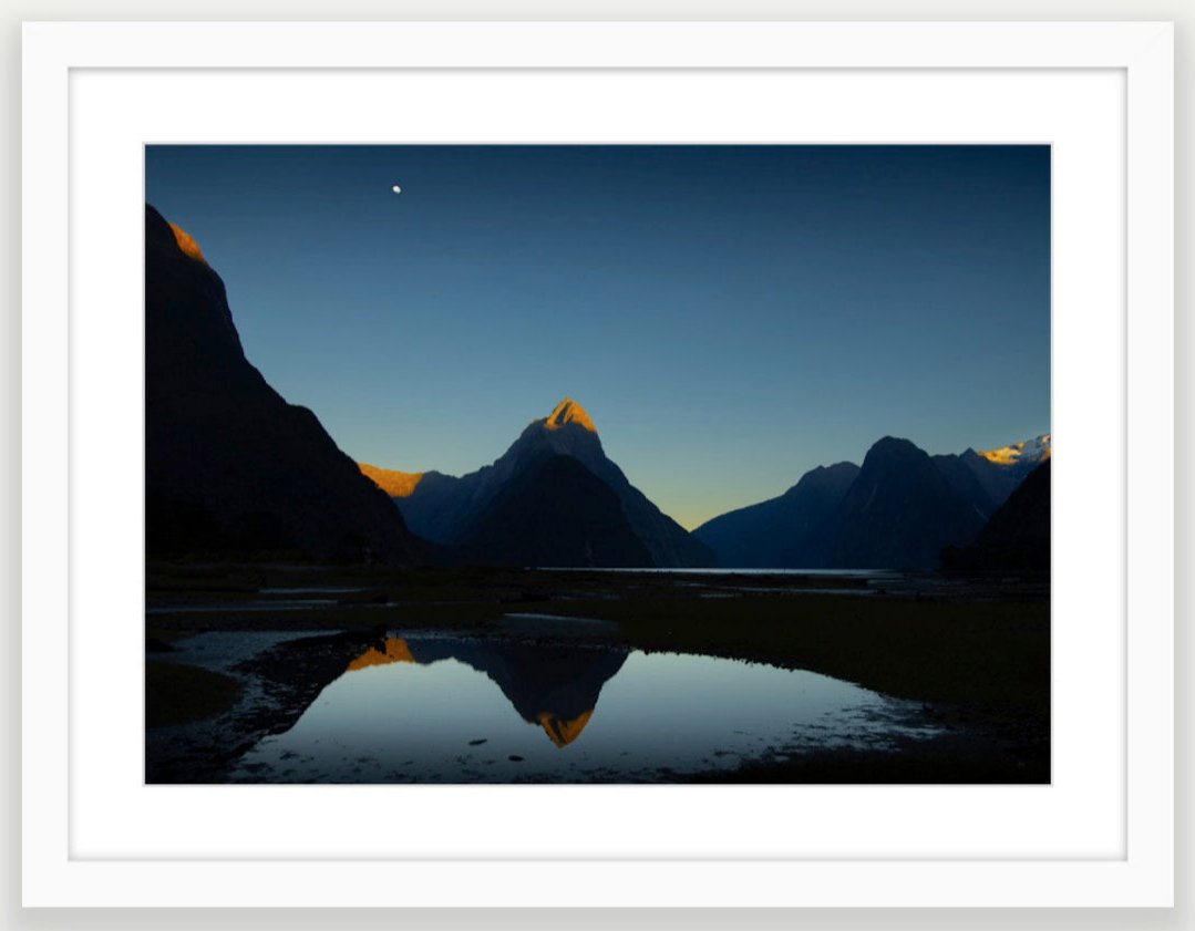 White wood frame  (594 x 420mm print, 720 × 550mm frame) Mitre te atakura Mitre Peak dressed in her red tips of dawn, te ata kura, on a rare and beautifully clear, still, morning. Milford Sound New Zealand. A2 size and A3 size