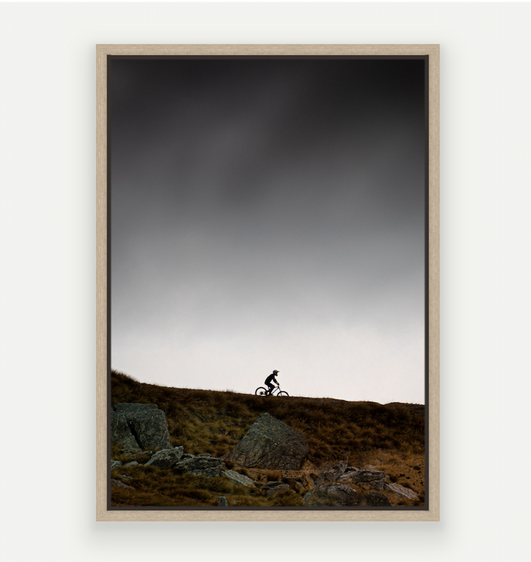 Silhouette of a Mountain biker at Cardrona against a dark stormy summer sky.