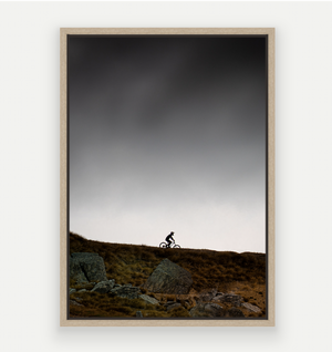 Silhouette of a Mountain biker at Cardrona against a dark stormy summer sky.
