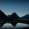 Mitre Peak at dawn, showing her red tips of dawn known as te atakura in te rea Māori. All reflected in the still dawn sea of Milford Sound